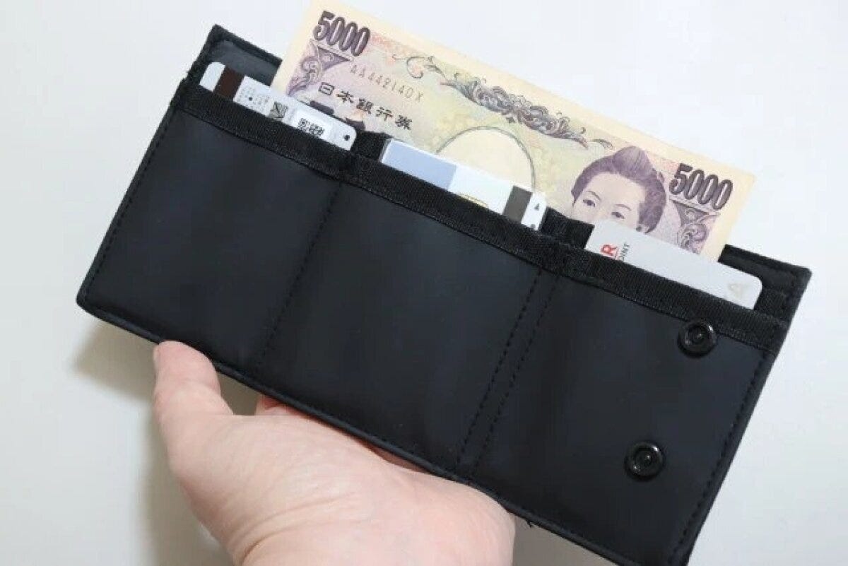 黒い三つ折り財布を開きお札とカードが見える