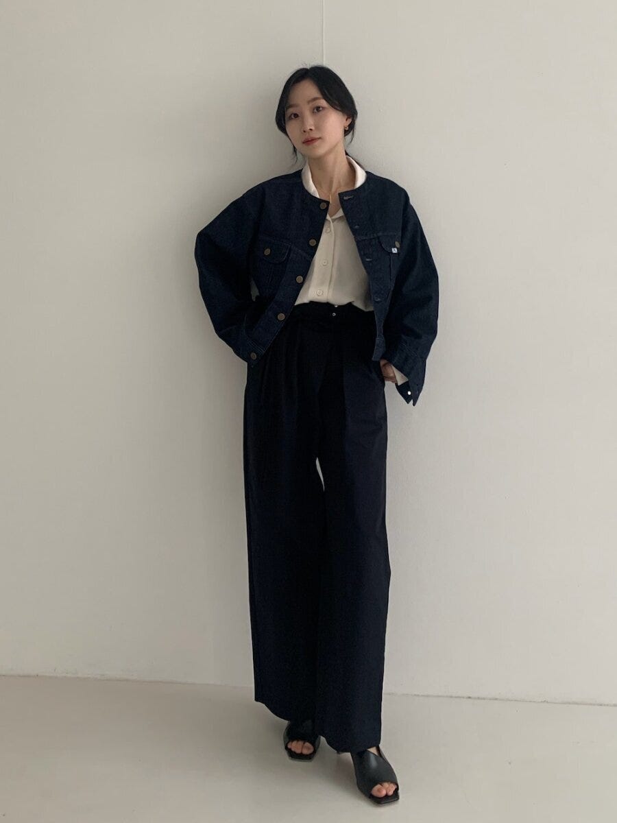 ショート丈ノーカラーGジャンと黒ワイドパンツを着た女性