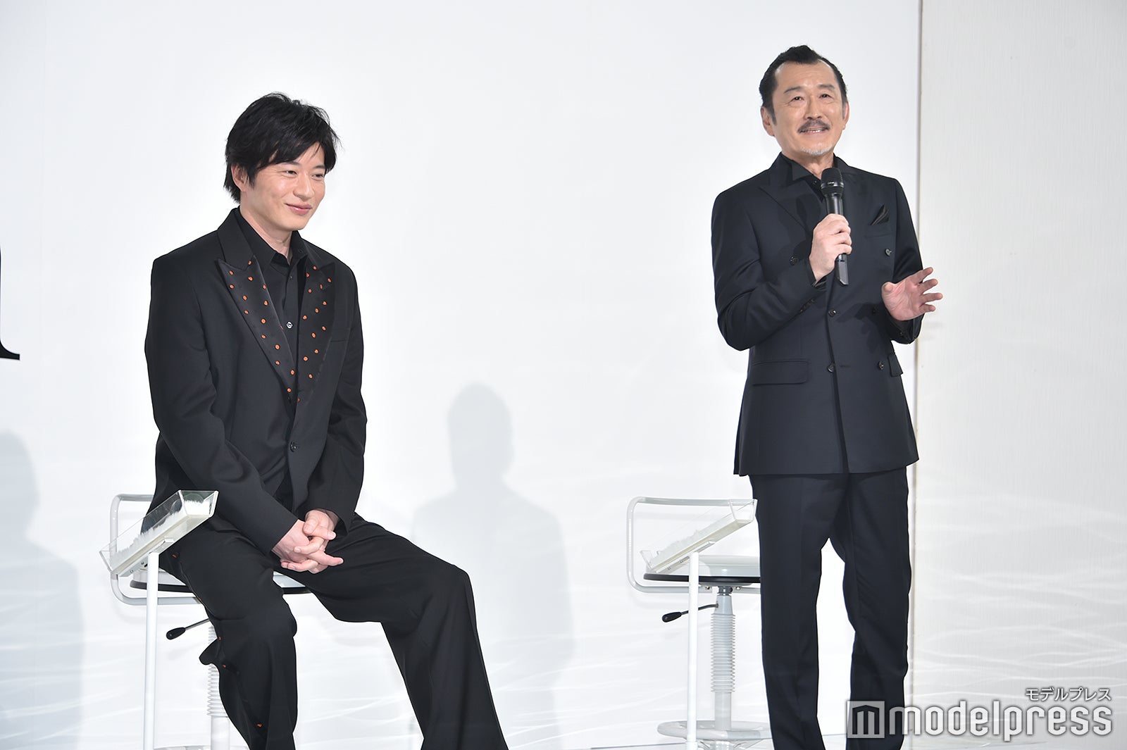 吉田鋼太郎の話をニコニコ笑顔で聞いている田中圭（C）モデルプレス