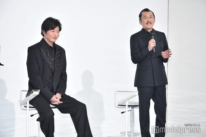 吉田鋼太郎の話をニコニコ笑顔で聞いている田中圭(C)モデルプレス