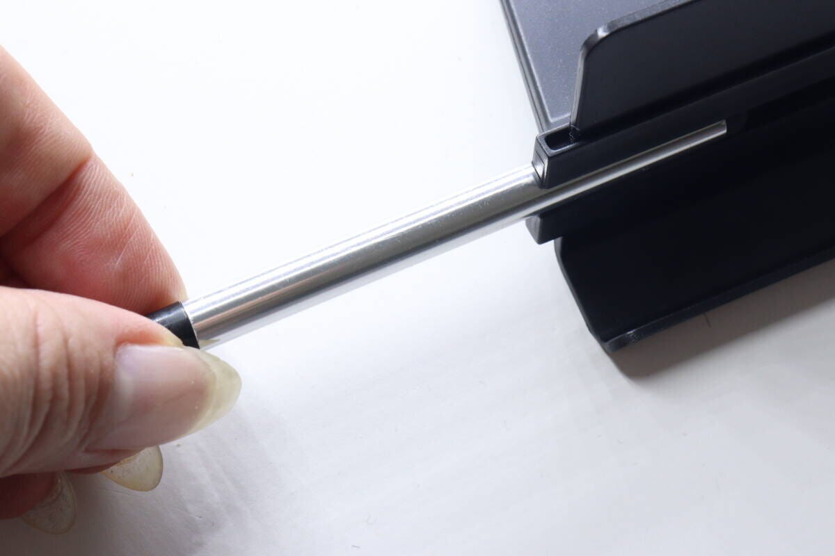 指でスマホスタンドから収納されている銀色のタッチペンを引き抜いている様子。