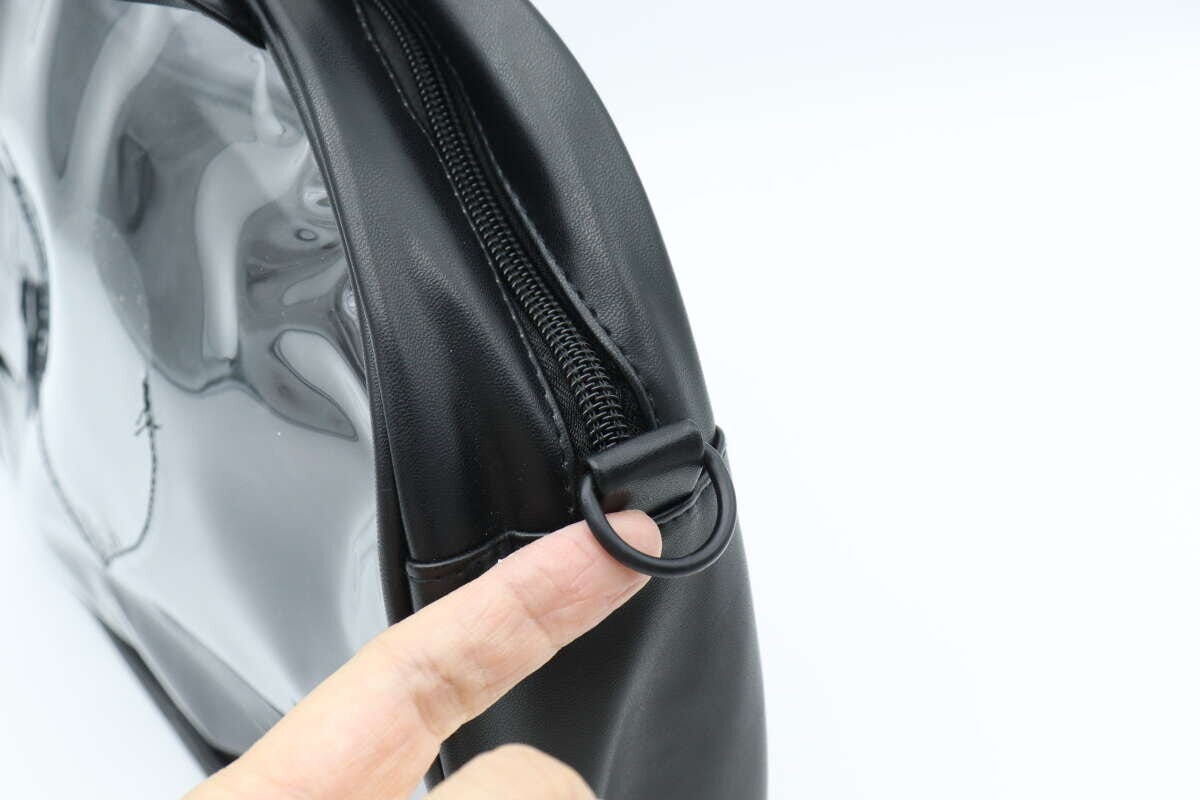 黒いクリアバッグ側面にあるショルダーストラップ用Dカンを指で示している