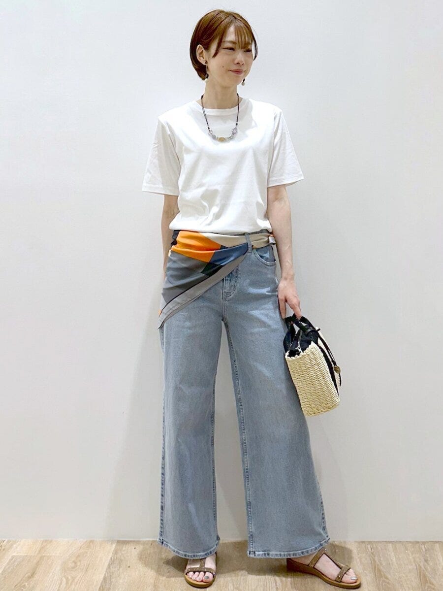白Tとデニム、柄スカーフを巻いた女性がかごバッグを持つ
