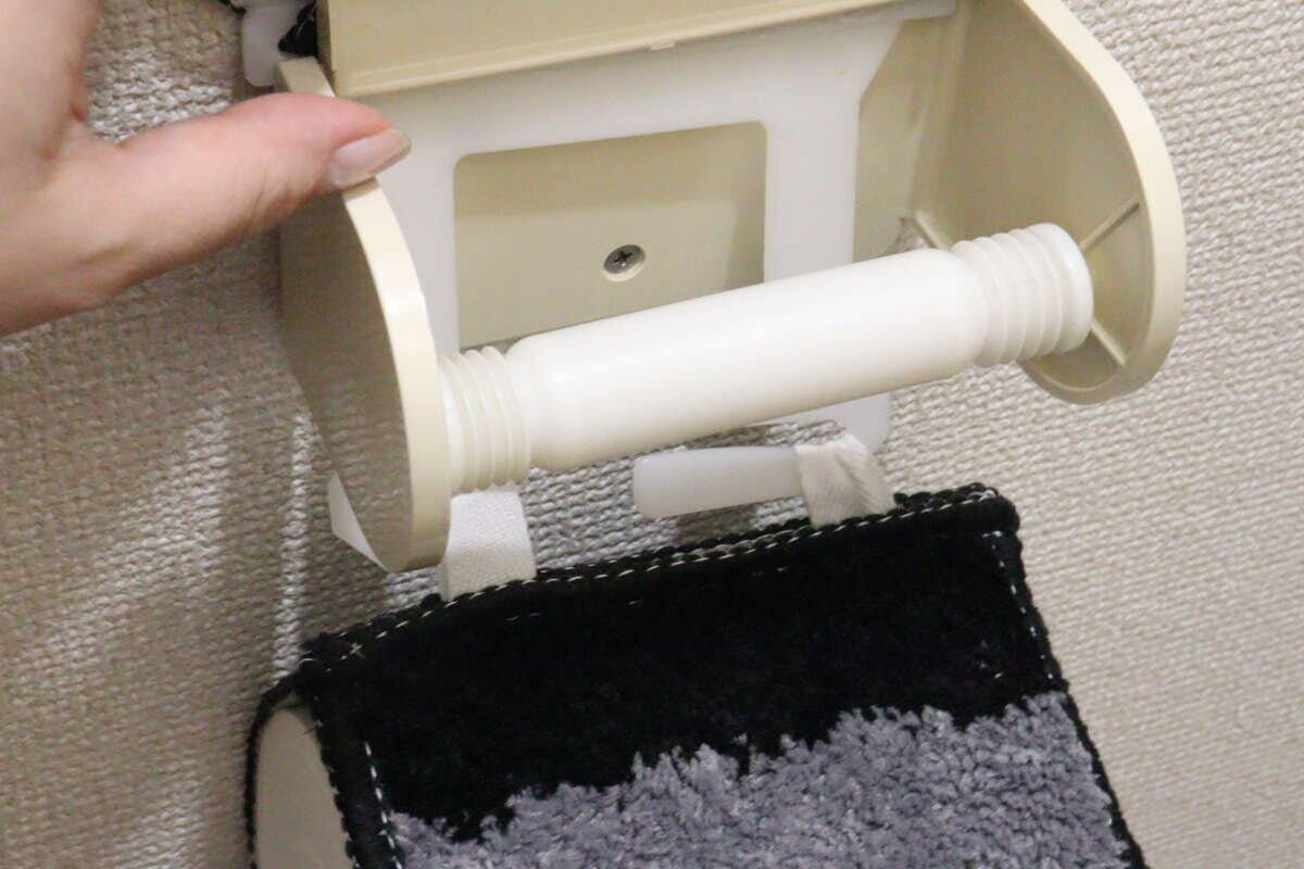 女性の手が古い蛇腹タイプのトイレットペーパーホルダーを外している 女性の手が古い蛇腹タイプのトイレットペーパーホルダーを外している