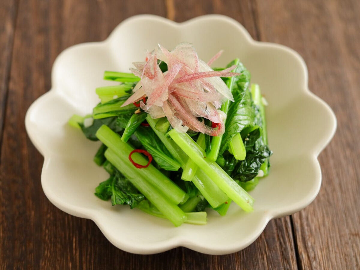 白い花形の皿に千切りみょうががトッピングされた小松菜のペペロンチーノ風炒め 白い花形の皿に千切りみょうががトッピングされた小松菜のペペロンチーノ風炒め