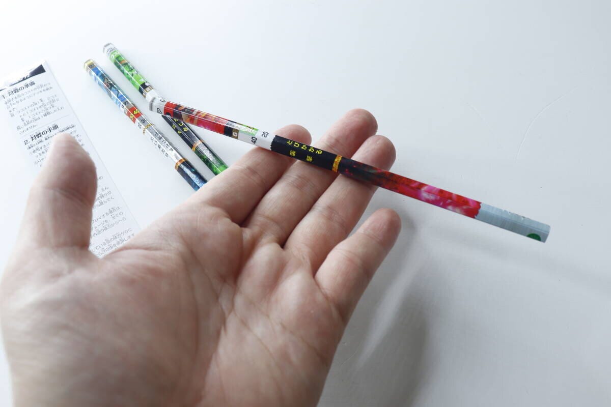 手のひらに『蟲神器バトルえんぴつ』を乗せて見せている