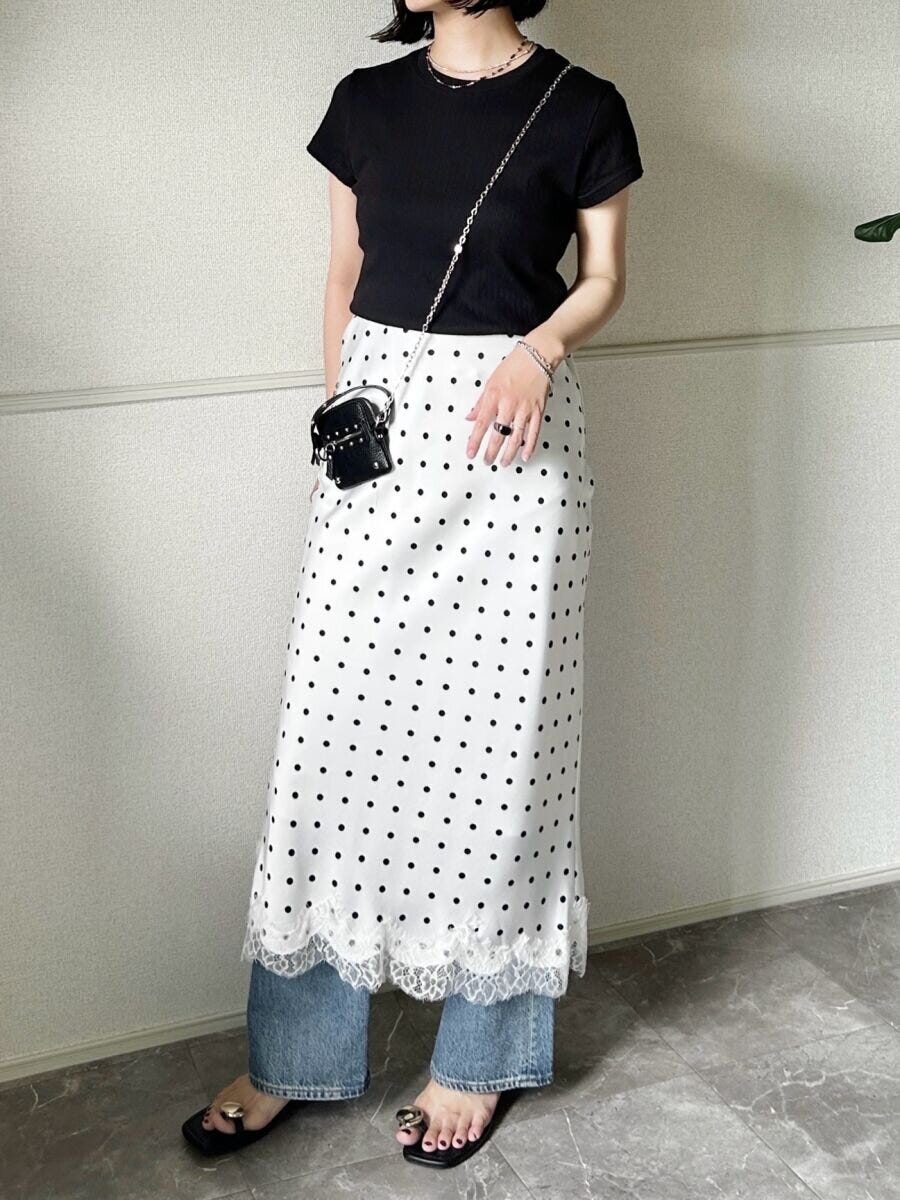 黒いリブミニTシャツとデニム、白いドット柄レーススカートを重ね着した女性の全身 黒いリブミニTシャツとデニム、白いドット柄レーススカートを重ね着した女性の全身