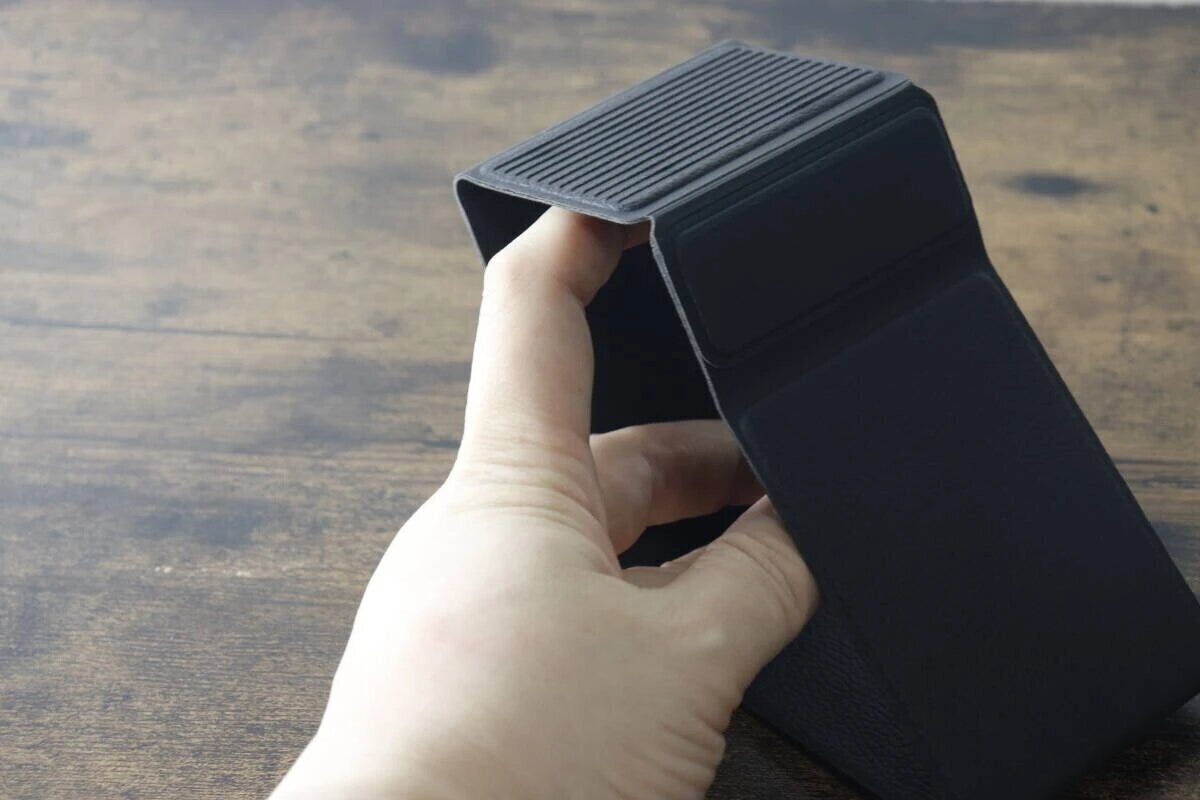 黒い折りたたみスマホスタンドを開いて組み立てている様子