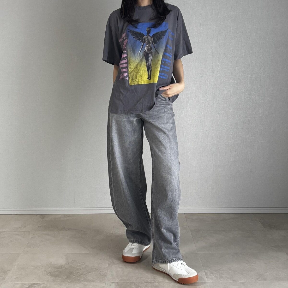 グレーのダメージTシャツとグレーデニムを着用した女性
