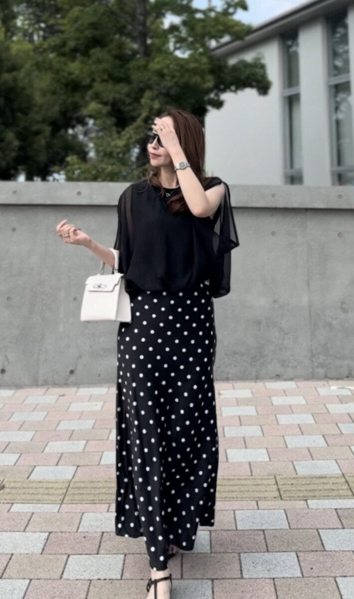 黒いトップスとドット柄マーメイドスカートを着用し、サングラスをかけた女性の全身 黒いトップスとドット柄マーメイドスカートを着用し、サングラスをかけた女性の全身