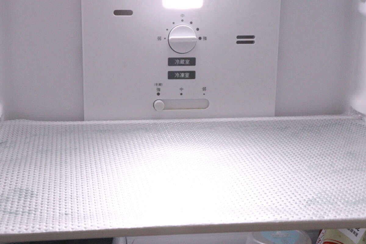 冷蔵庫の棚に敷かれたクリアな冷蔵庫マット。奥に温度調節ダイヤルが見える