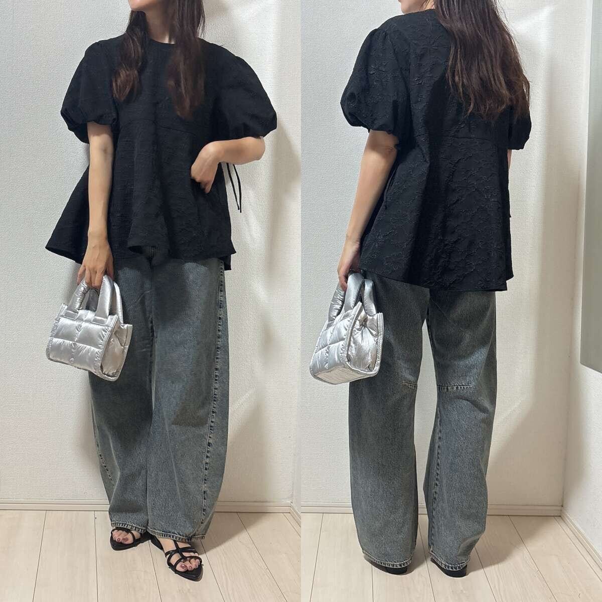 黒いパフスリーブブラウスとバレルジーンズの女性