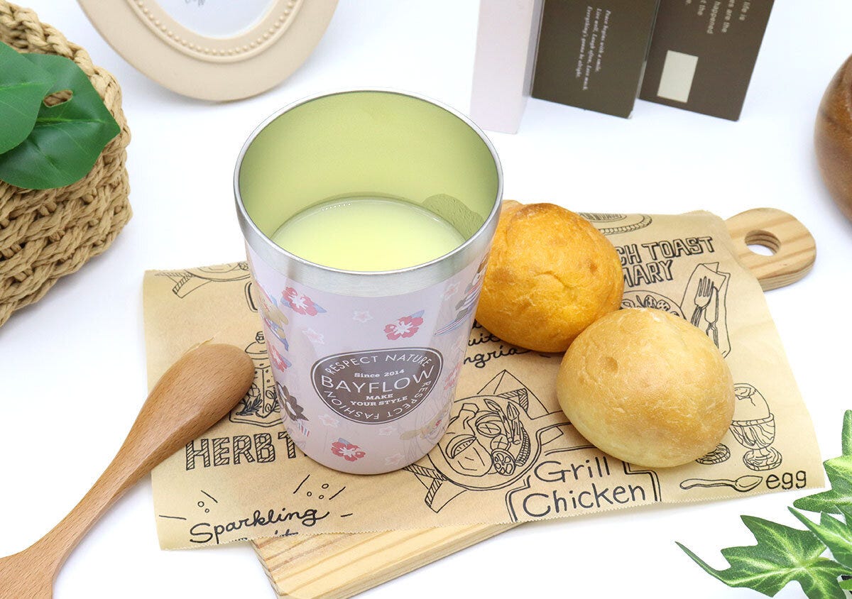 ピンクタンブラーに飲み物、パン、木製スプーンが置かれたテーブル ピンクタンブラーに飲み物、パン、木製スプーンが置かれたテーブル