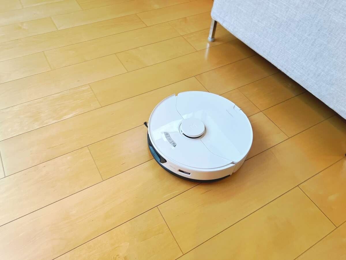 木のフローリングを掃除する白いロボット掃除機 木のフローリングを掃除する白いロボット掃除機