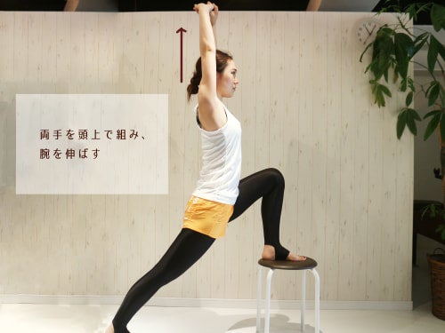 両手を頭上で組み、腕を伸ばす動