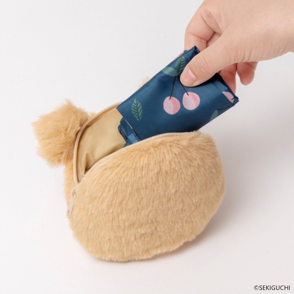 モンチッチのぬいぐるみチャームの中にエコバッグを収納している手元