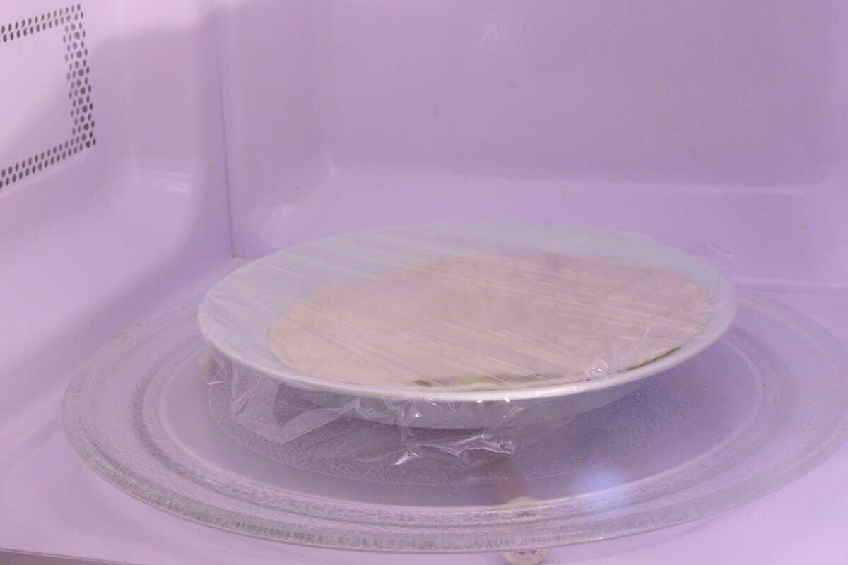 電子レンジの中でラップをかけて温められているトルティーヤ 電子レンジの中でラップをかけて温められているトルティーヤ