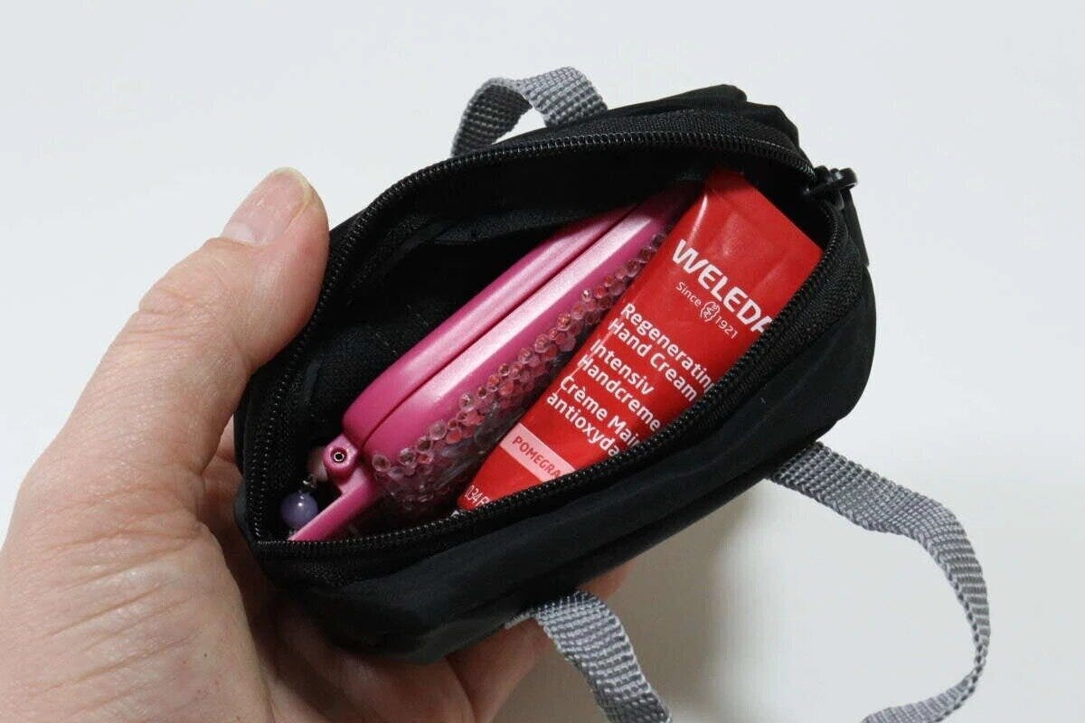 黒いミニポーチの中にピンクのヘアクリップと赤いハンドクリームが入っている