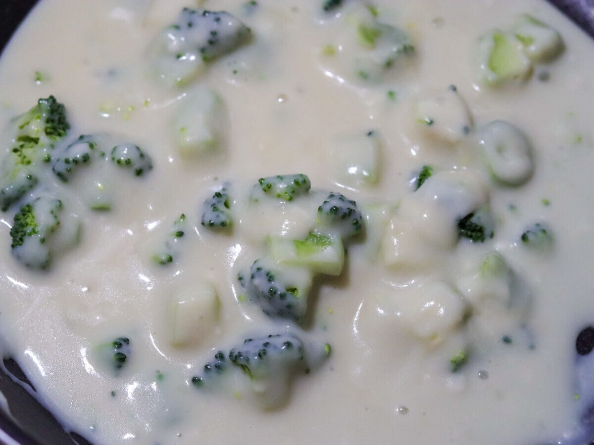 フライパンでブロッコリーが白いクリームソースに絡まって煮えている様子 フライパンでブロッコリーが白いクリームソースに絡まって煮えている様子