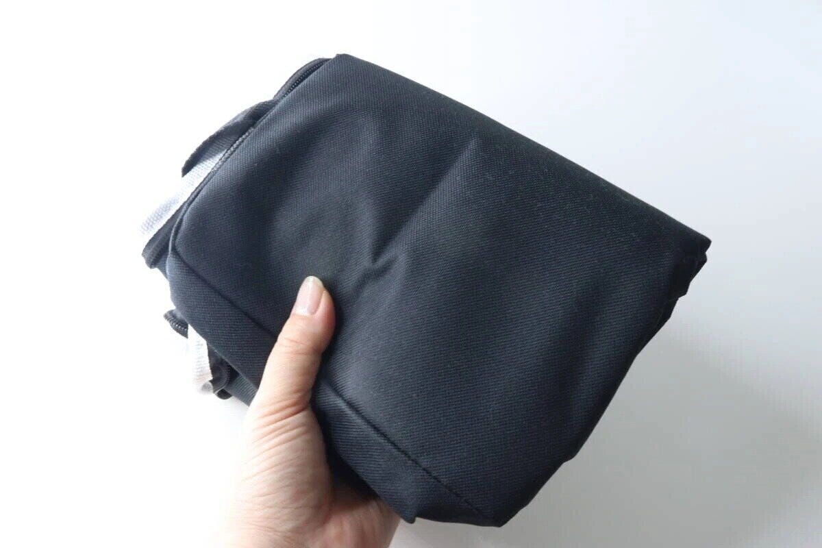 黒いソフトクーラーバッグを片手でコンパクトに折りたたんでいる様子