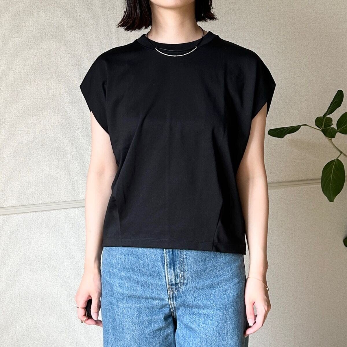 黒いフレンチスリーブTシャツとデニムを着用した女性が正面を向いている