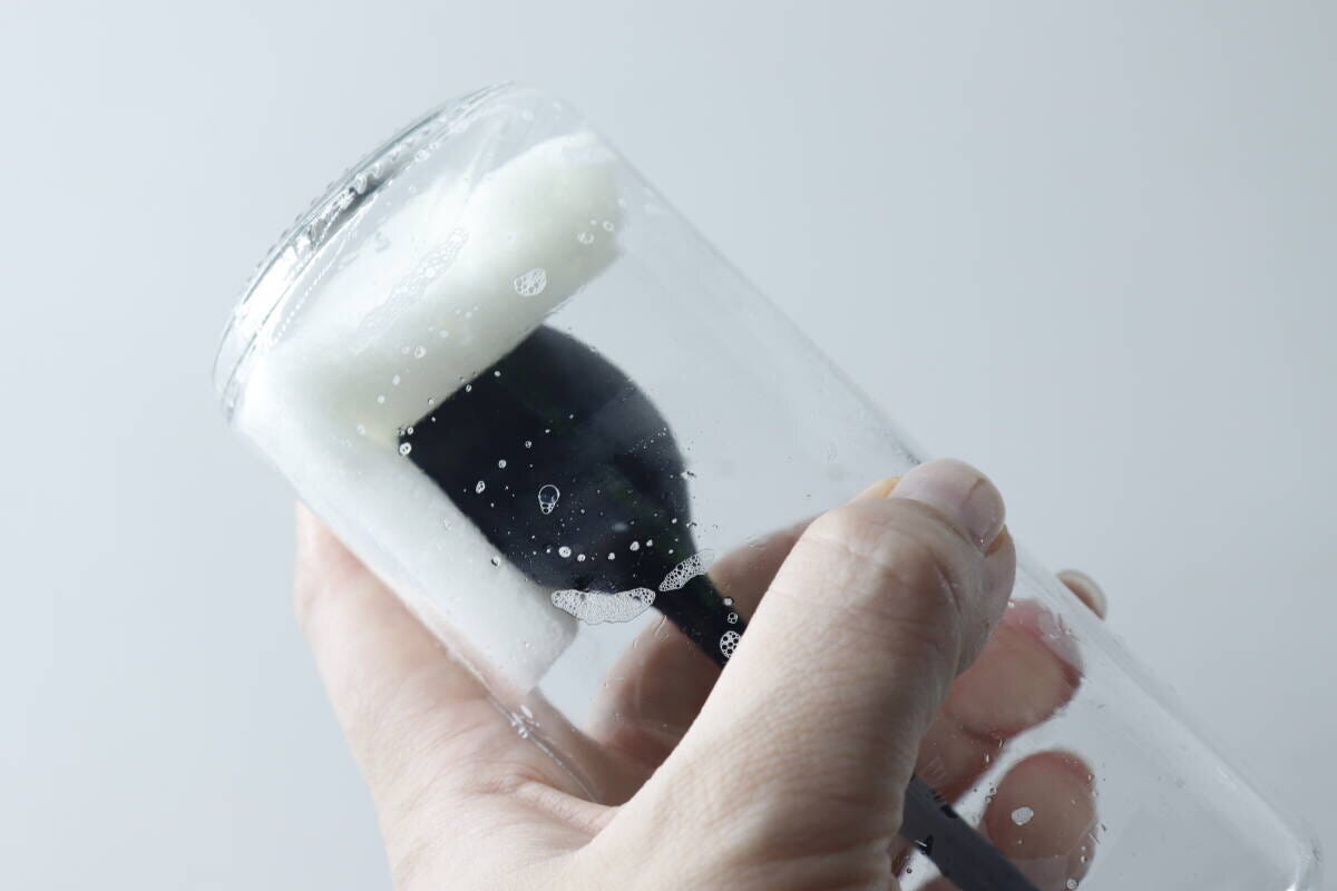 オイルボトルを使い捨てスポンジで洗っている手の様子 オイルボトルを使い捨てスポンジで洗っている手の様子