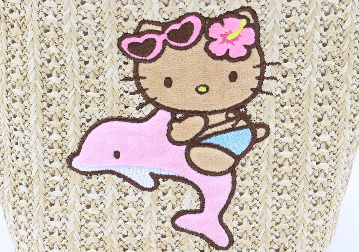 かごバッグに刺繍された日焼けハローキティとピンクのイルカのアップ