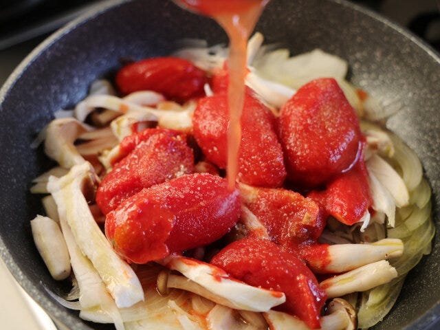 トマト缶を上から入れたら、砂糖を振り、しょう油と水を入れる。