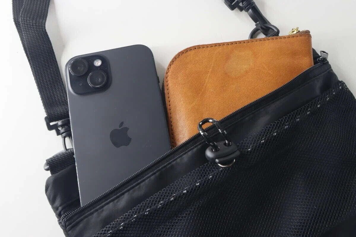 黒いショルダーバッグのメッシュポケットにスマホと財布が収納されている
