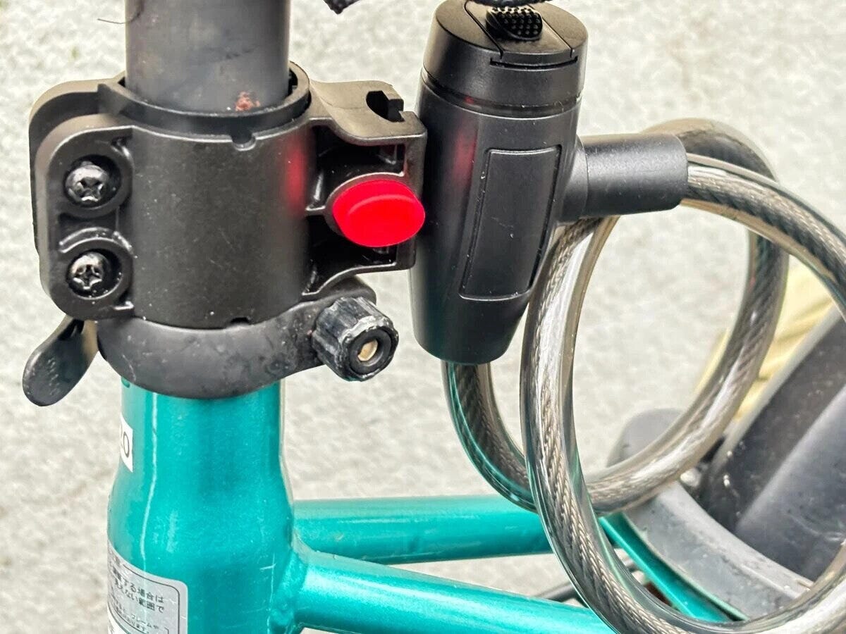 緑色の自転車のサドル下支柱にワイヤーロックのブラケットが取り付けられている様子 緑色の自転車のサドル下支柱にワイヤーロックのブラケットが取り付けられている様子