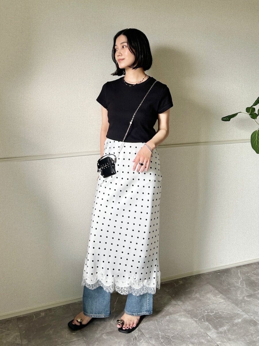黒トップスとドット柄スカート、デニムをレイヤードした女性 黒トップスとドット柄スカート、デニムをレイヤードした女性