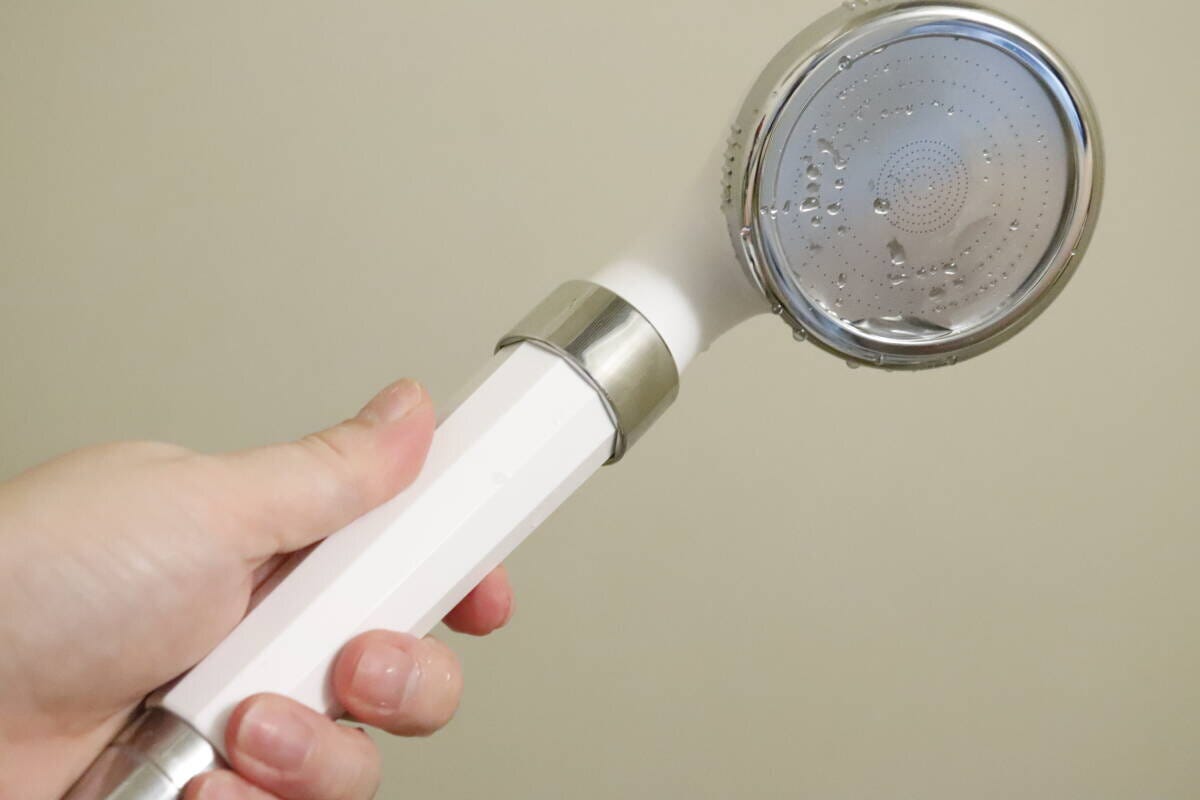 手で持ったシャワーヘッドに水滴が付いている様子