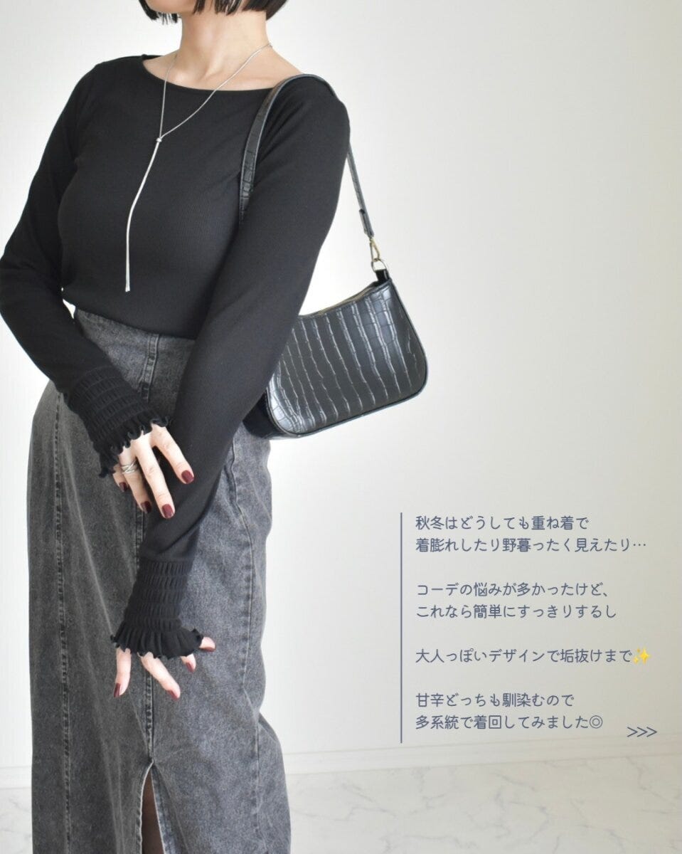 黒の長袖トップスとグレーのデニムスカートを着た女性の全身ショット