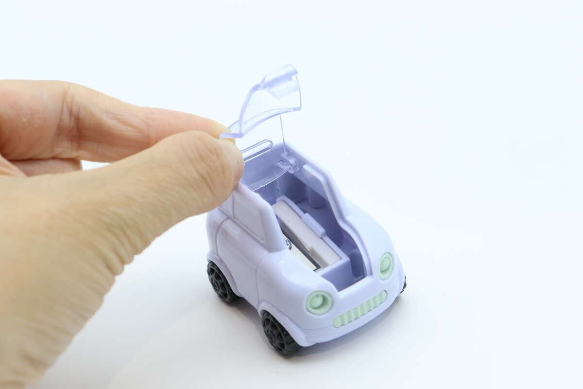 右手で車型鉛筆削りのボンネット部分を開けている 右手で車型鉛筆削りのボンネット部分を開けている