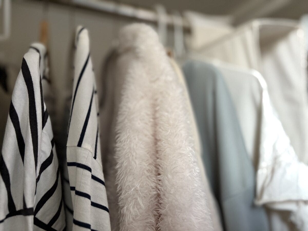 クローゼットの中でストライプ柄と白いファー素材の服が並ぶ
