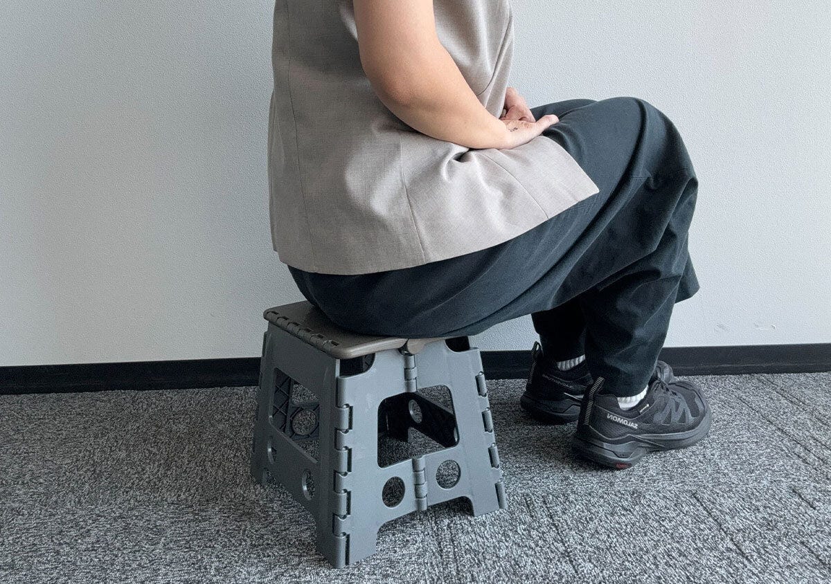 展開した折りたたみイスに座る女性の横からの全身 展開した折りたたみイスに座る女性の横からの全身