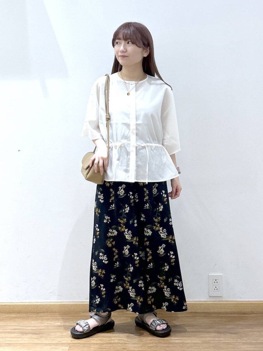 白のドローストリングブラウスと花柄ロングスカートを着た女性 白のドローストリングブラウスと花柄ロングスカートを着た女性