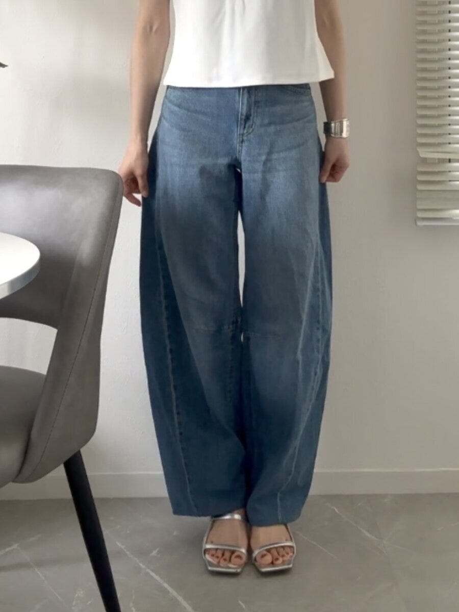 明るいブルーのバレルレッグジーンズを着用し立つ女性の全身 明るいブルーのバレルレッグジーンズを着用し立つ女性の全身