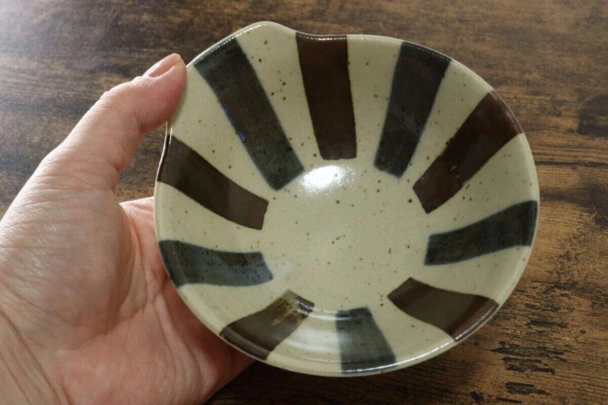 女性の手が茶色と白のストライプ柄の和風とんすいを持っている 女性の手が茶色と白のストライプ柄の和風とんすいを持っている