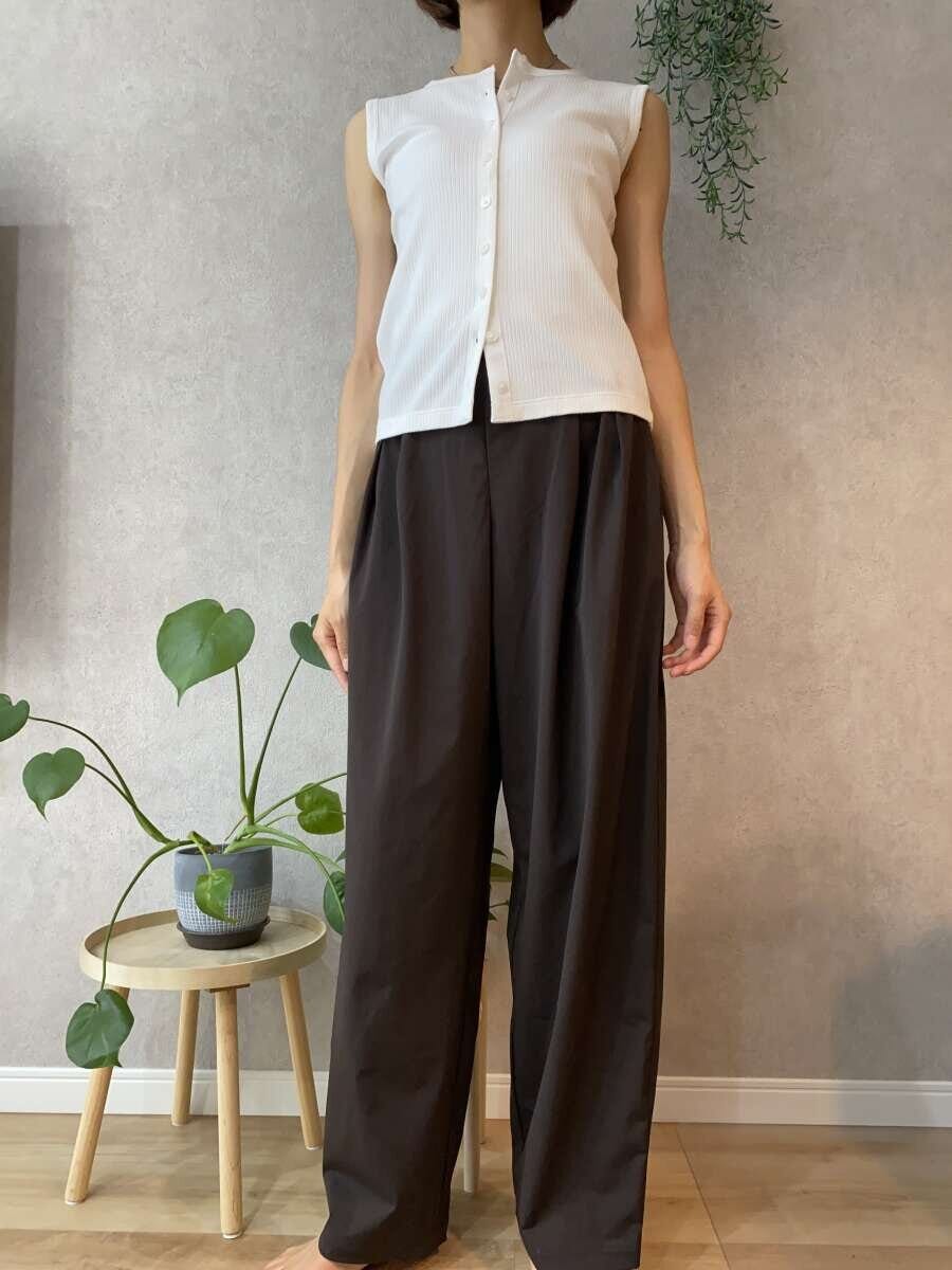 ダークブラウンのワイドパンツと白いトップスを着た女性