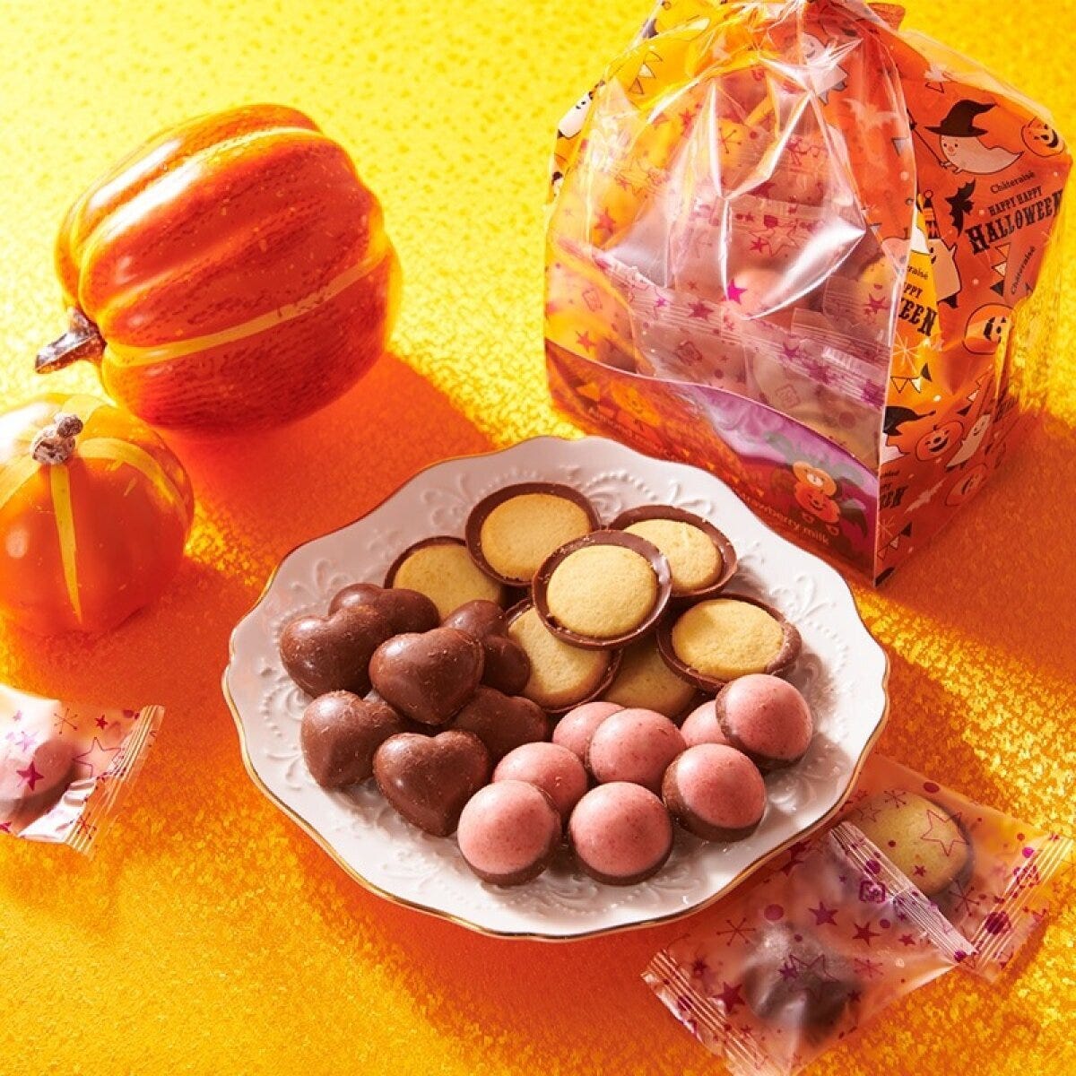 ハロウィン柄の袋と、ハートや丸い形のチョコレートが白い皿に並べられている