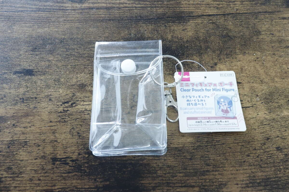 透明なミニフィギュア用ポーチと商品タグが木目のテーブルに置かれている
