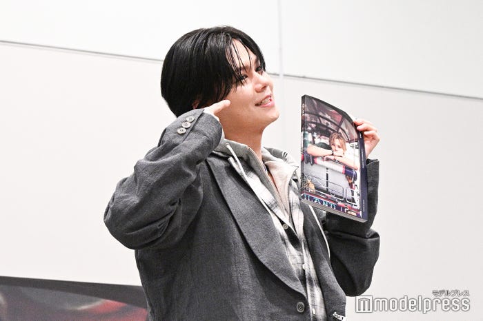 写真集を指している途中で自分のことも指し始めるカイ(C)モデルプレス