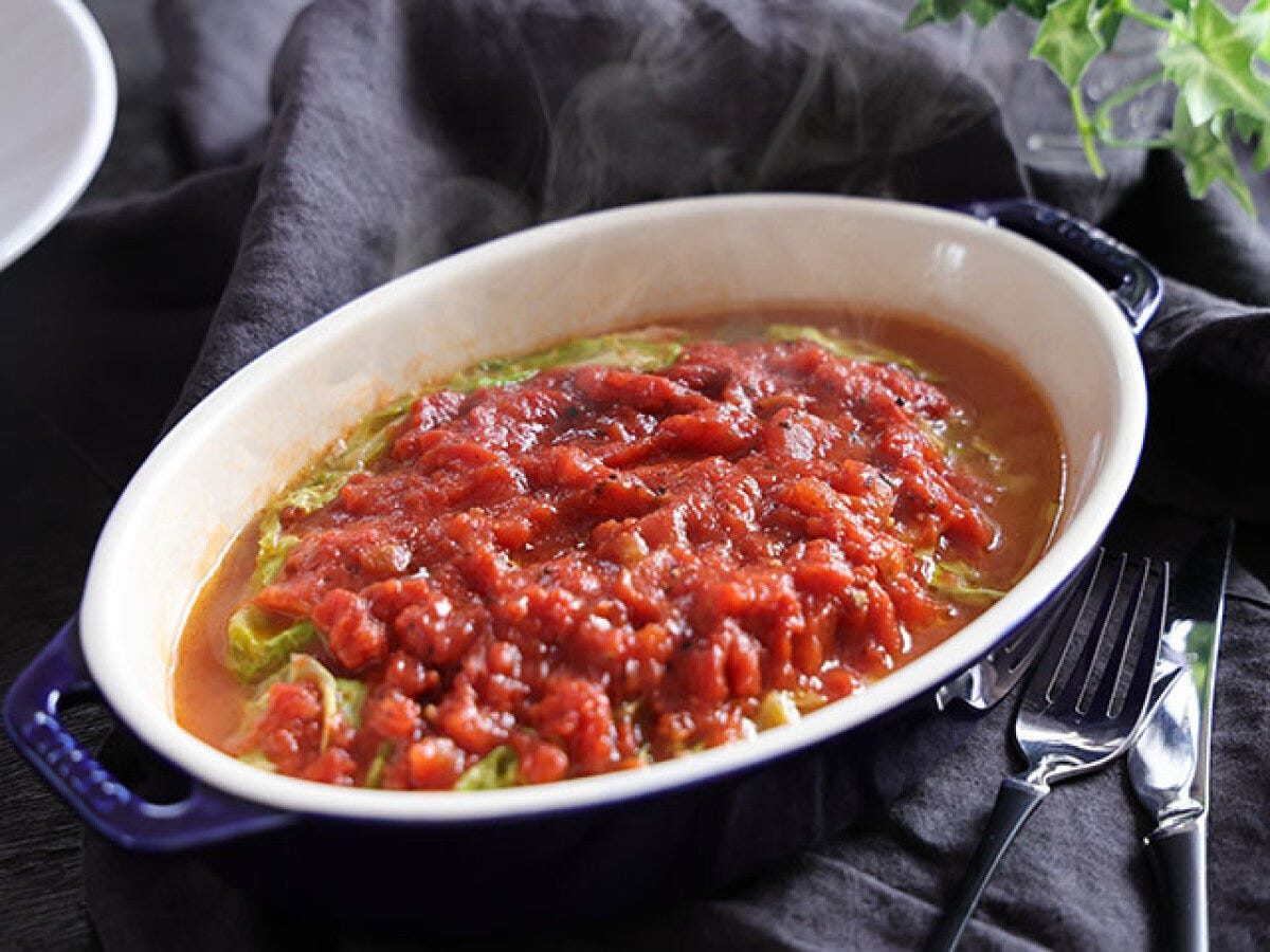 濃紺のオーバル耐熱容器に盛られた春キャベツと豚肉のトマトチーズ蒸しの完成品、湯気が立ち上っている様子