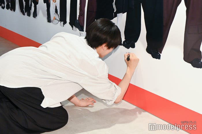 足元にメッセージを書く本島純政(C)モデルプレス