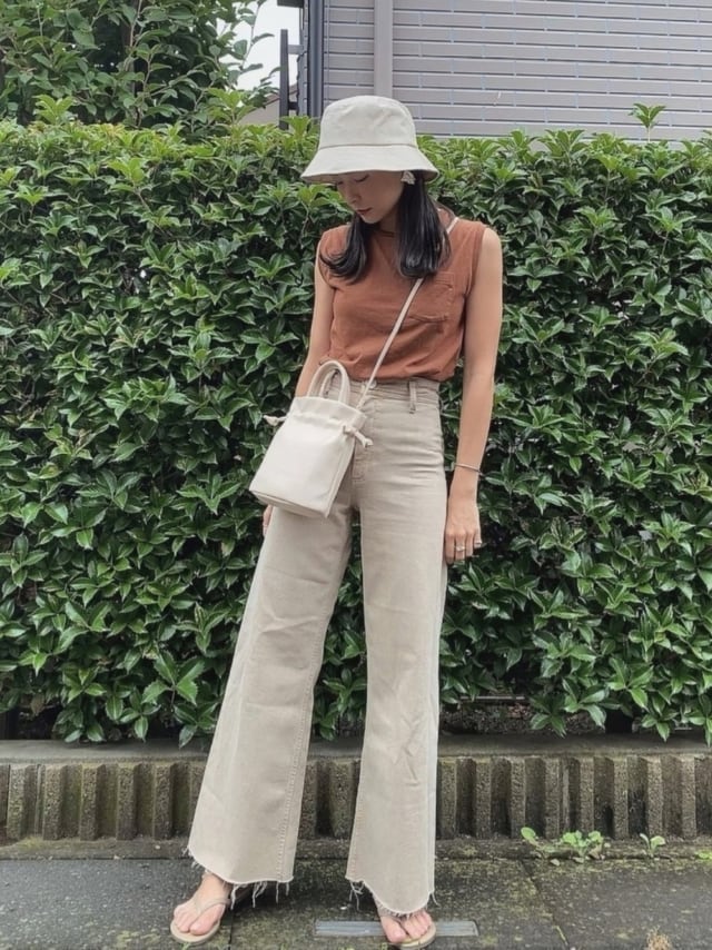 ブラウンのタンクトップにZARAのベージュのストレートデニムパンツを合わせた女性