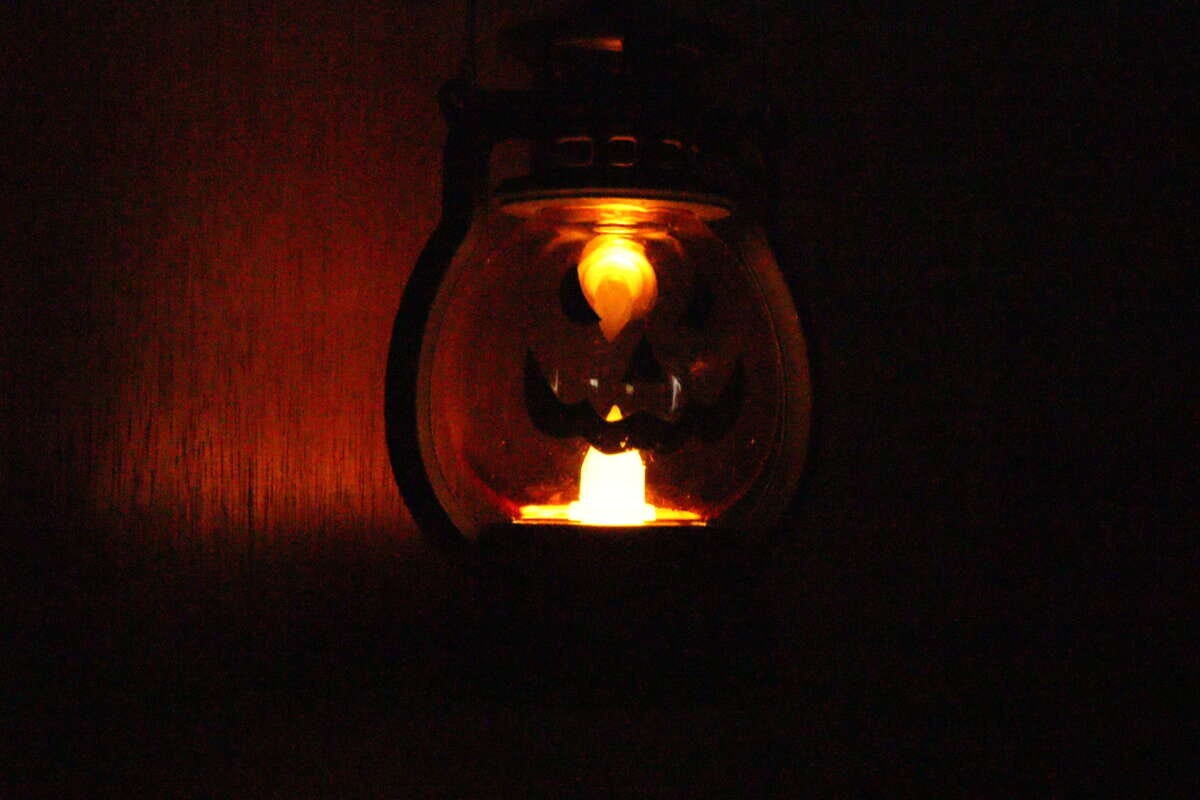 暗闇でLEDランタンが点灯し、かぼちゃの顔がぼんやりと光っている 暗闇でLEDランタンが点灯し、かぼちゃの顔がぼんやりと光っている