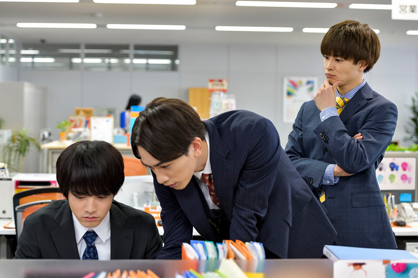 仕事中の安達（赤楚衛二）と黒沢（町田啓太）、2人を見つめる六角（草川拓弥／超特急） （C）豊田悠／SQUARE ENIX・「30 歳まで童貞だと魔法使いになれるらしい」製作委員会