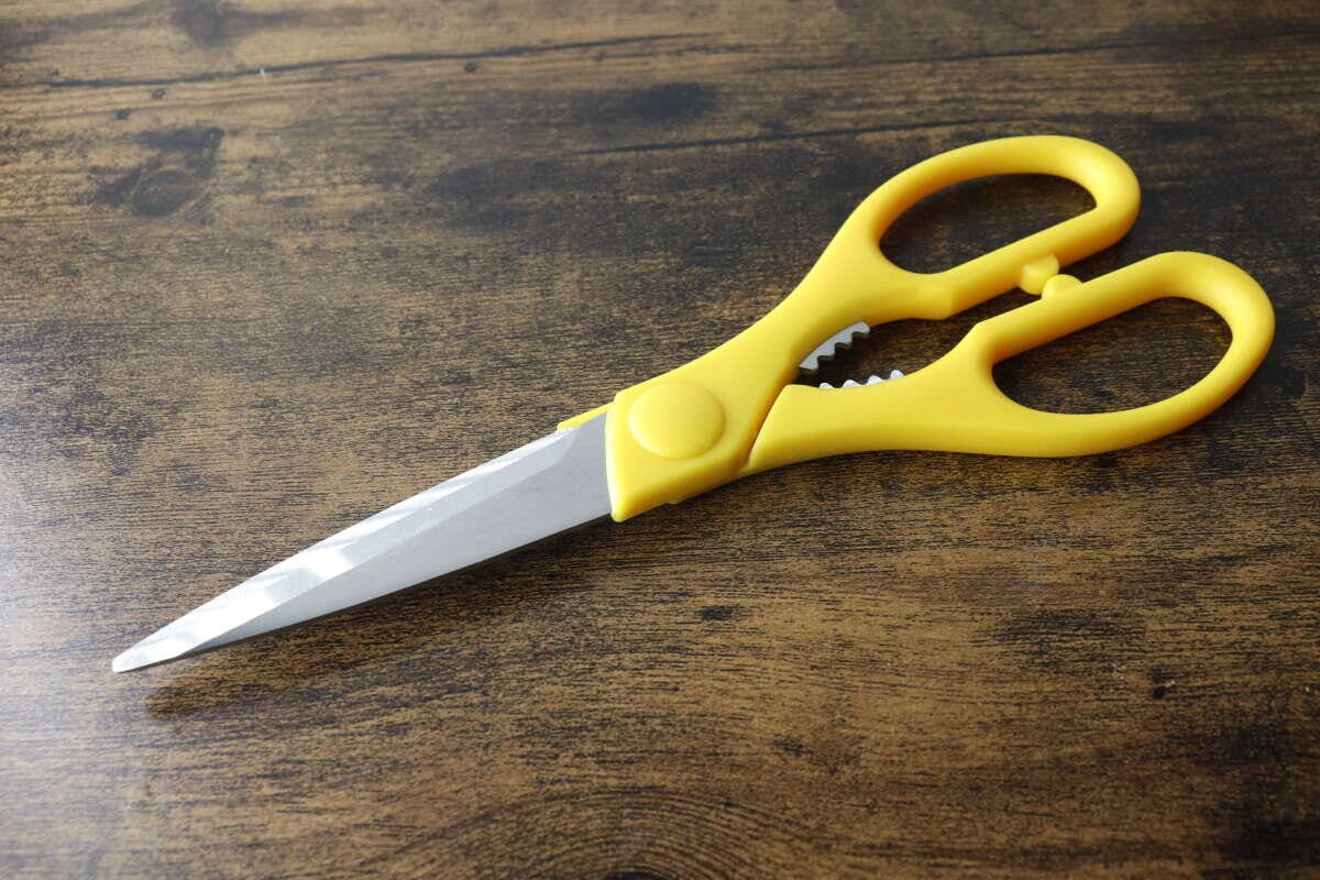 木目調のテーブルに置かれた黄色いダイソーキッチンハサミ 木目調のテーブルに置かれた黄色いダイソーキッチンハサミ