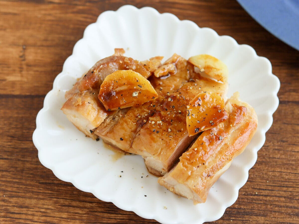 白い皿に盛ったにんにく山のもも肉に黒こしょうをふった完成写真